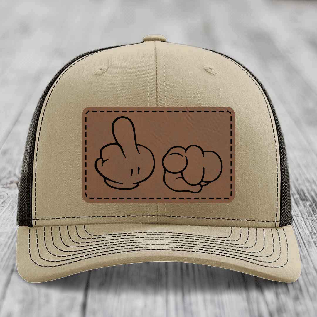 Beige trucker hat with brown leather patch showing cartoon hands making rude gesture.