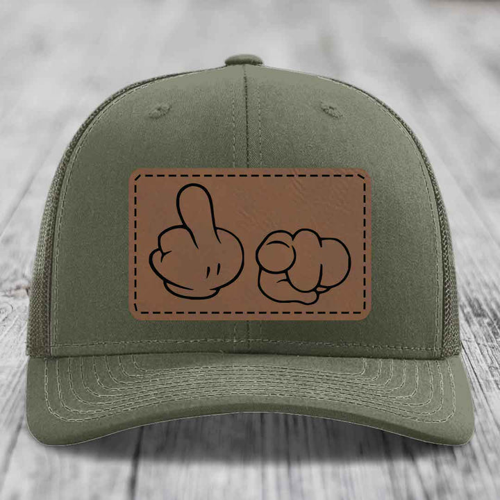 Olive green trucker hat with a brown leather patch showing cartoon hands making rude gestures.