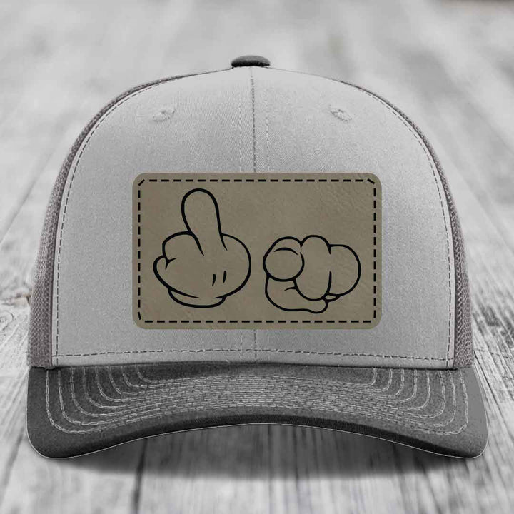 Grey trucker hat with a beige leatherette patch showing cartoon hands making rude gestures.