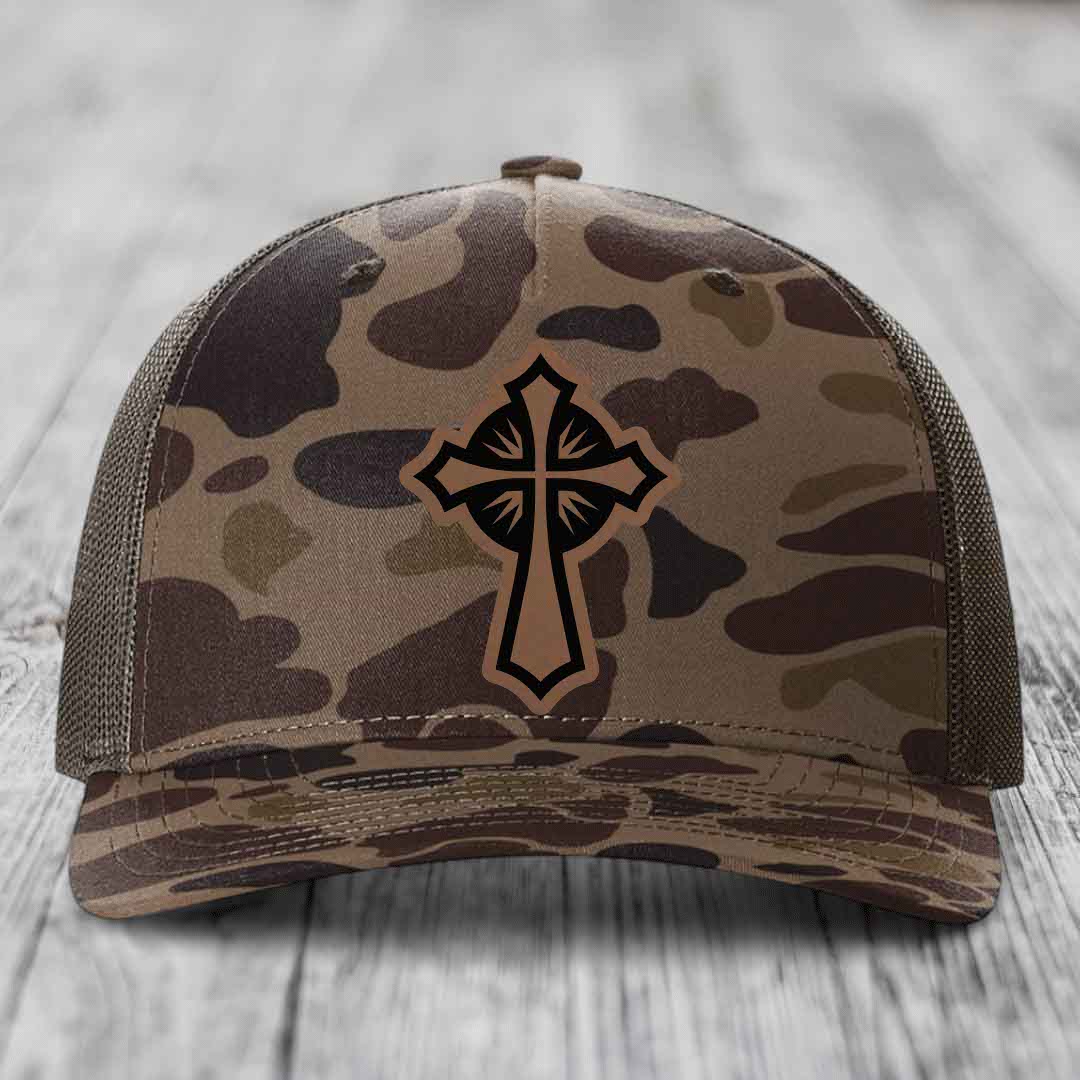 Camouflage trucker hat with a cross patch on the front.