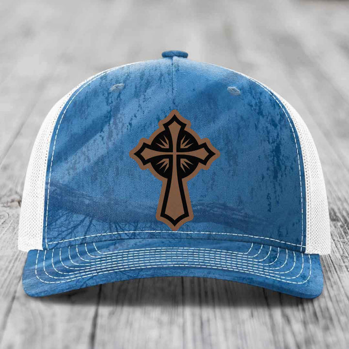 Blue and white trucker hat with a brown cross patch on the front.