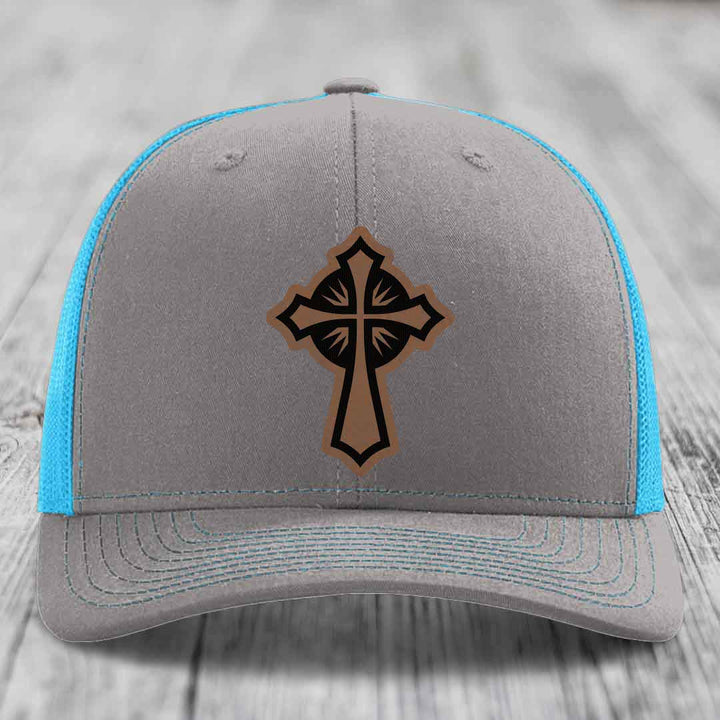 Grey trucker hat with blue mesh sides and a brown cross leather patch on front.