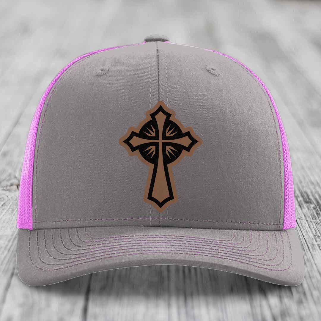 Grey trucker hat with pink mesh sides and a brown cross leather patch on front.