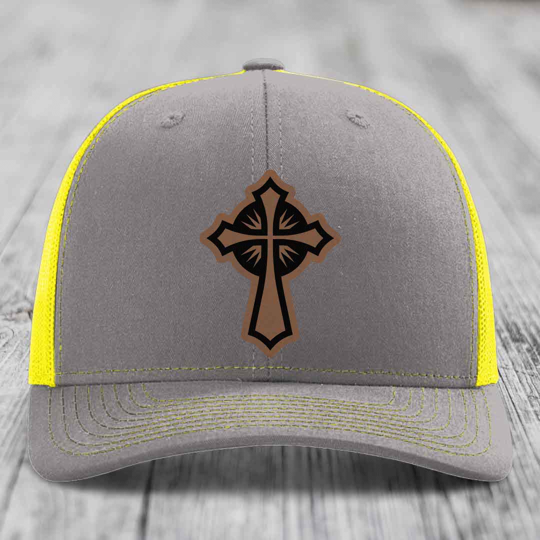 Grey trucker hat with yellow mesh and stitching, featuring a brown cross leather patch.