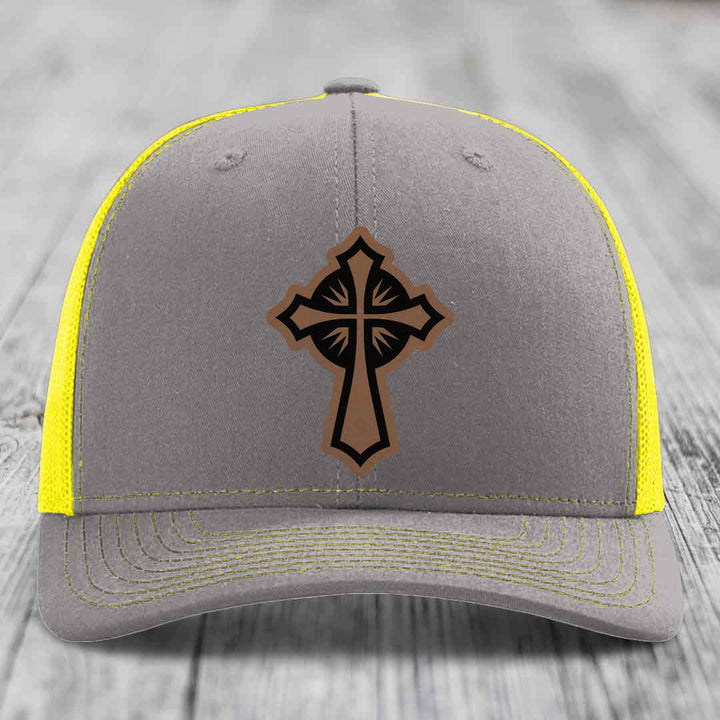 Grey trucker hat with yellow mesh and stitching, featuring a brown cross leather patch.