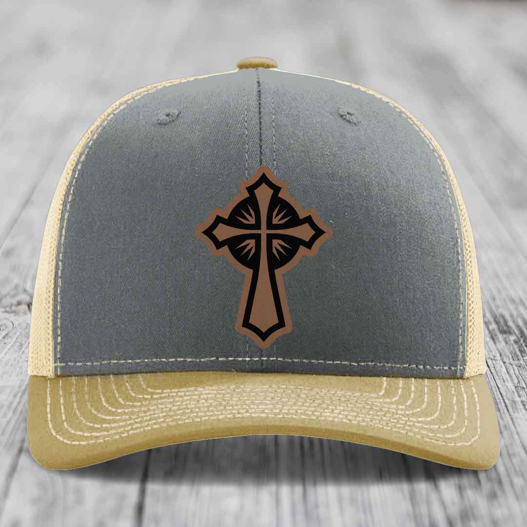 Grey and beige trucker hat with a brown leather cross patch on front.