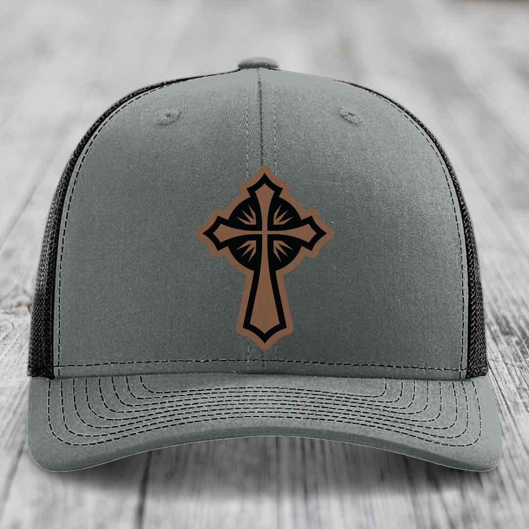 Grey trucker hat with a brown and black leather cross patch on front.