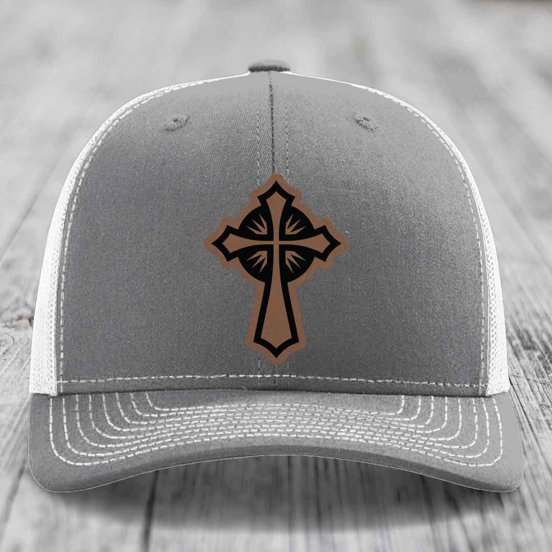 Grey trucker hat with brown and black cross leather patch on front.