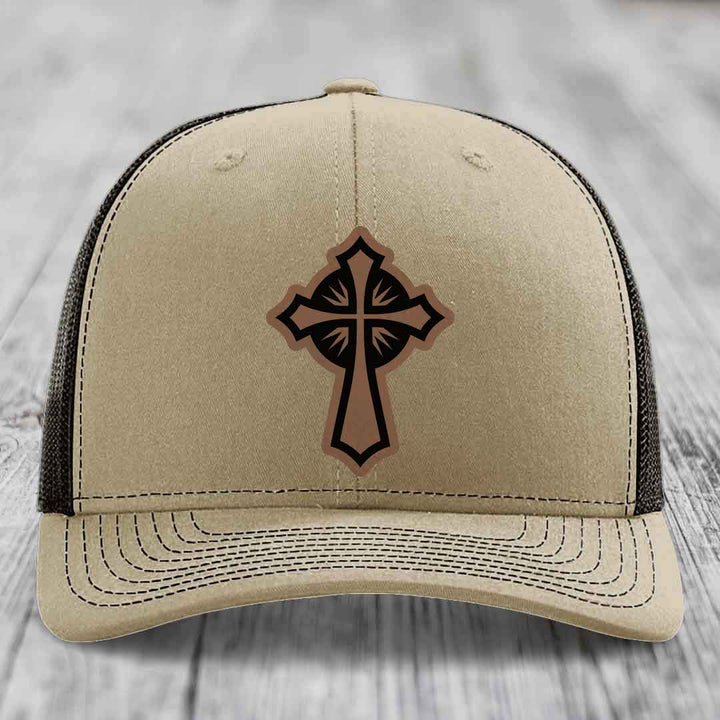 Beige trucker hat with a brown and black cross leather patch on the front.