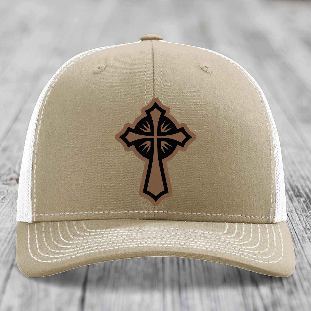 Tan trucker hat with black and brown cross leather patch on front.