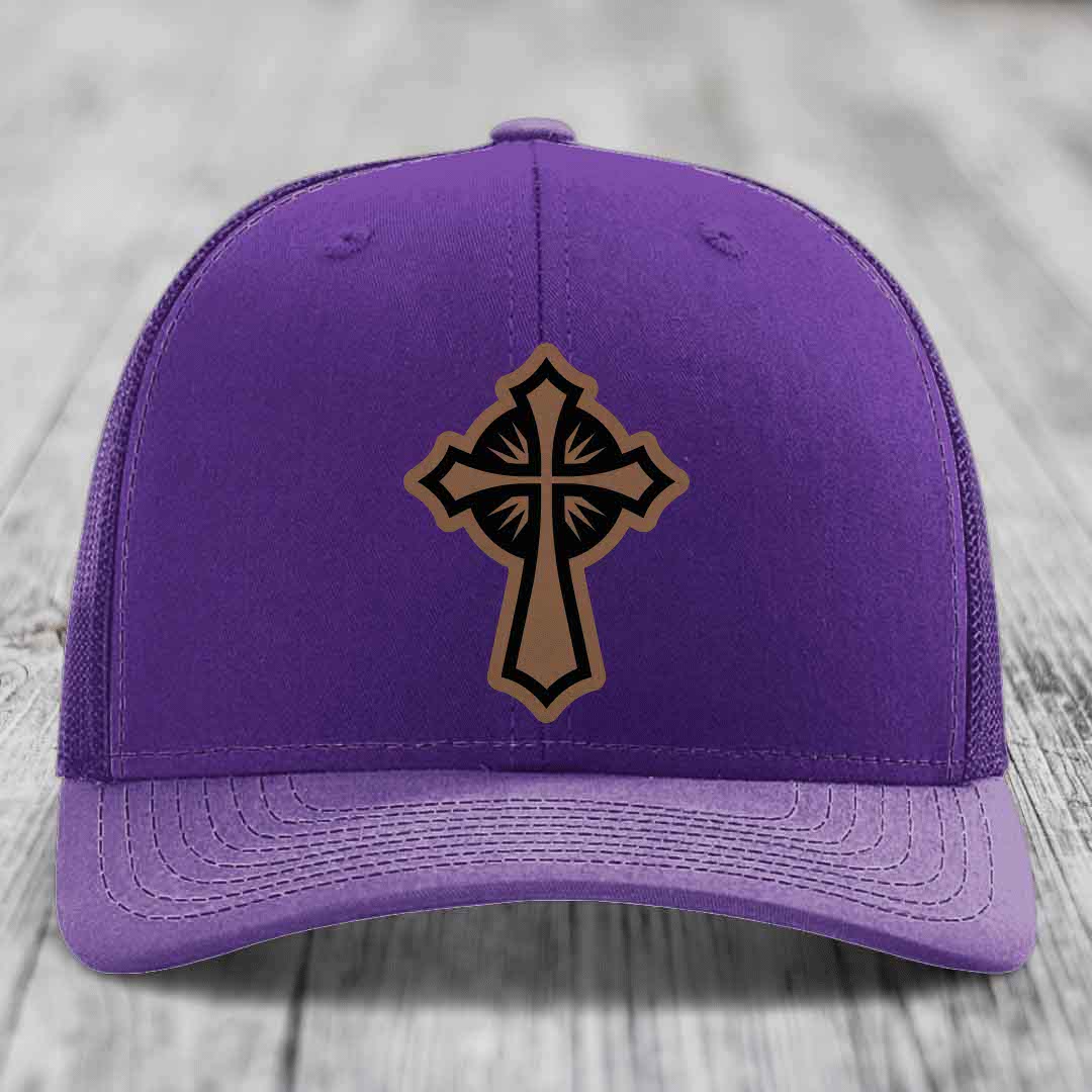 Purple trucker hat with a brown and black cross leather patch on the front.