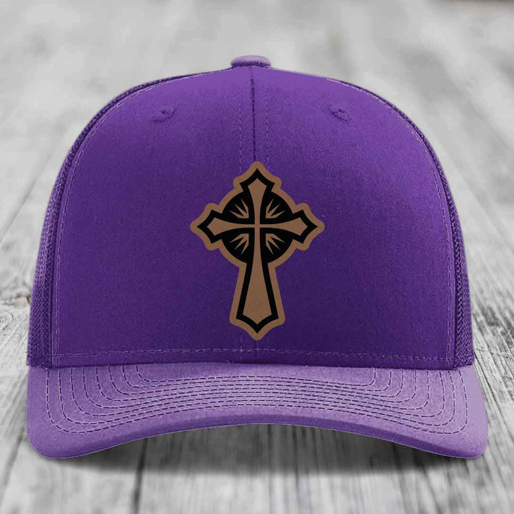 Purple trucker hat with a brown and black cross leather patch on the front.