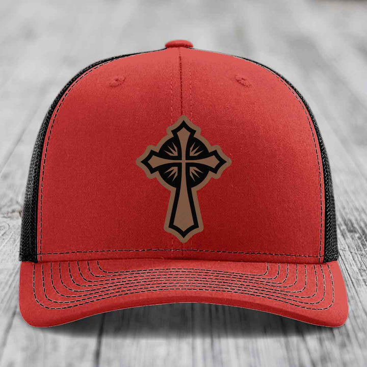 Red trucker hat with black mesh back and a brown cross leather patch on front.