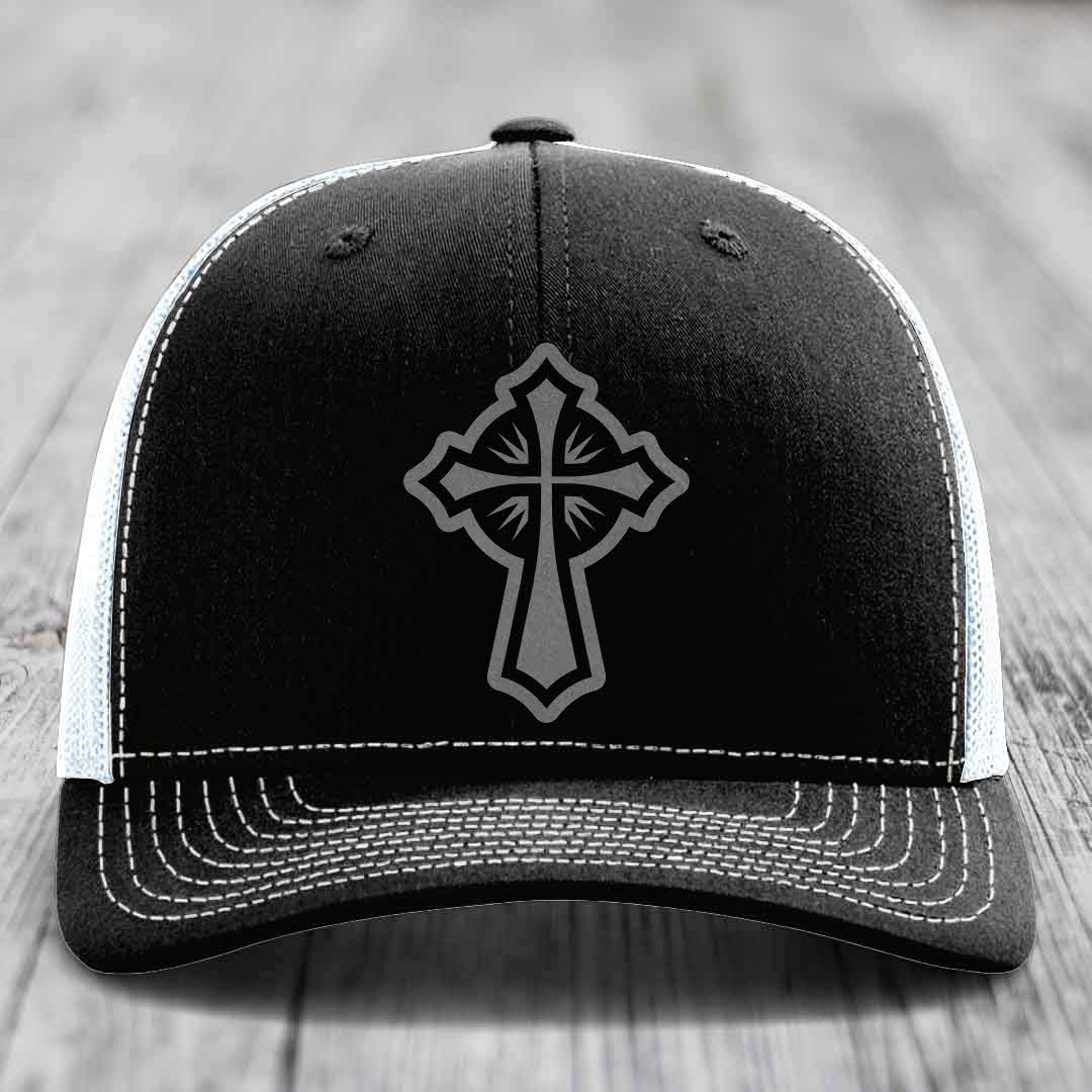 Black trucker hat with grey cross patch and white stitching on front panel.