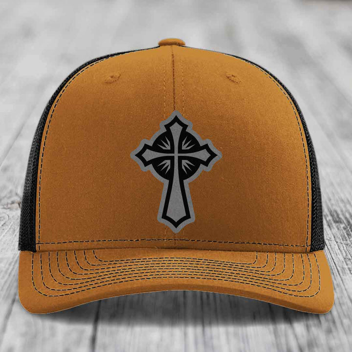 Tan trucker hat with black mesh back and gray cross patch on front.