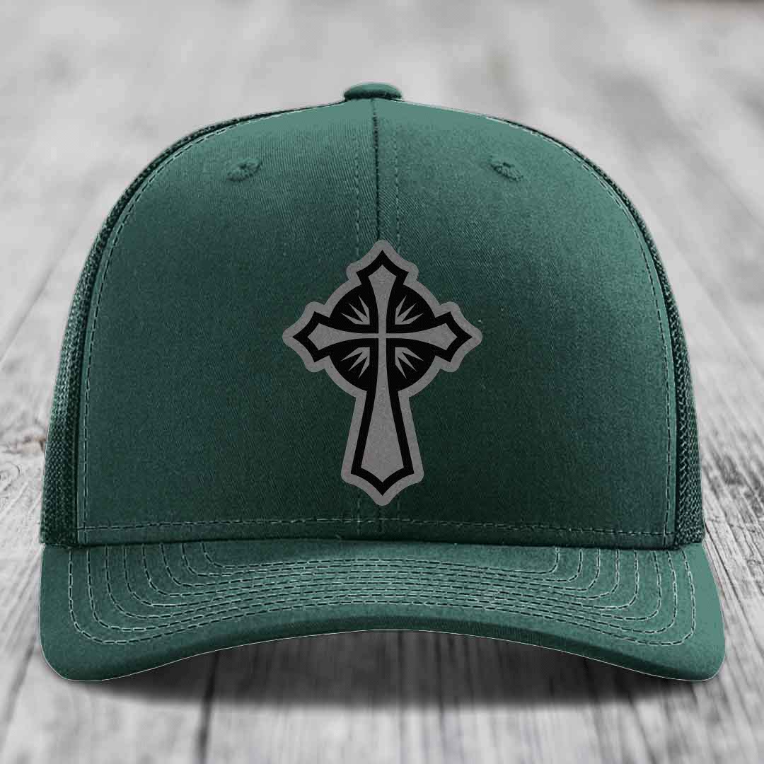 Dark green trucker hat with a black and grey cross patch on the front.