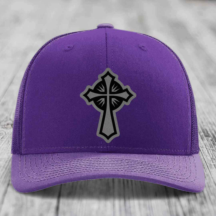 Purple trucker hat with a black and grey cross patch on the front.
