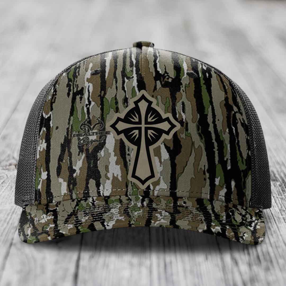 Camouflage trucker hat with a black and beige cross patch on the front.