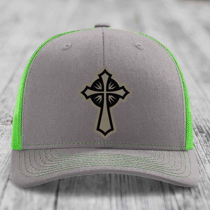 Grey trucker hat with black cross patch and neon green mesh sides.