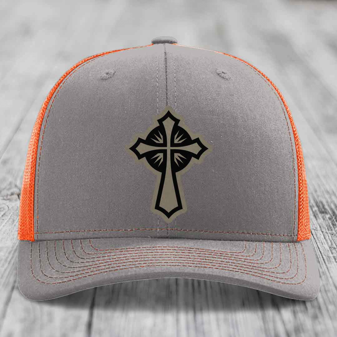 Grey trucker hat with orange mesh back and black cross patch on front.