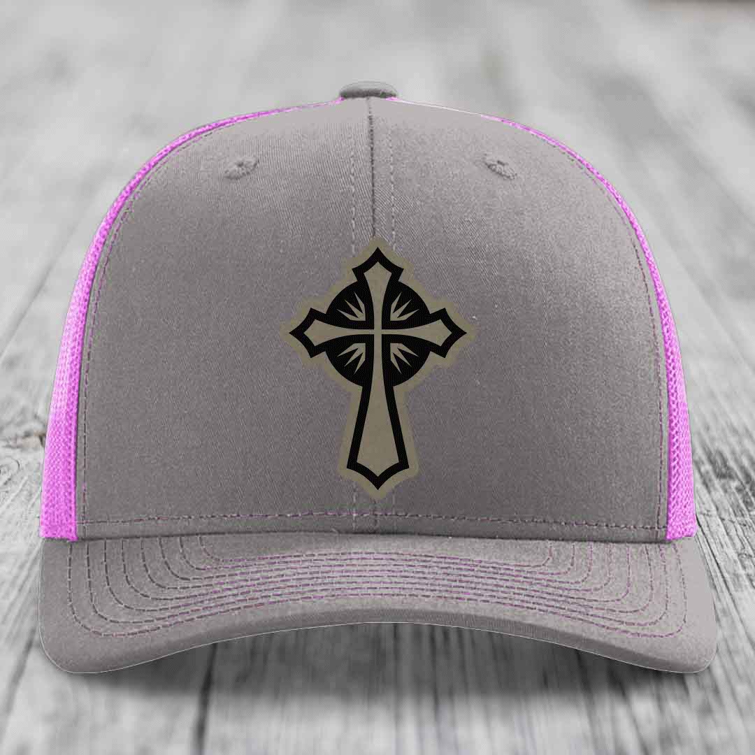 Grey trucker hat with black cross patch and pink mesh sides.