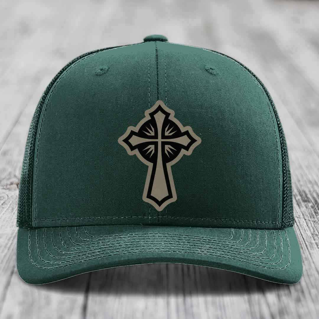 Dark green trucker hat with a cross patch on front, featuring black and beige design.