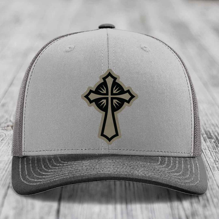 Grey trucker hat with black and tan cross leather patch on front.
