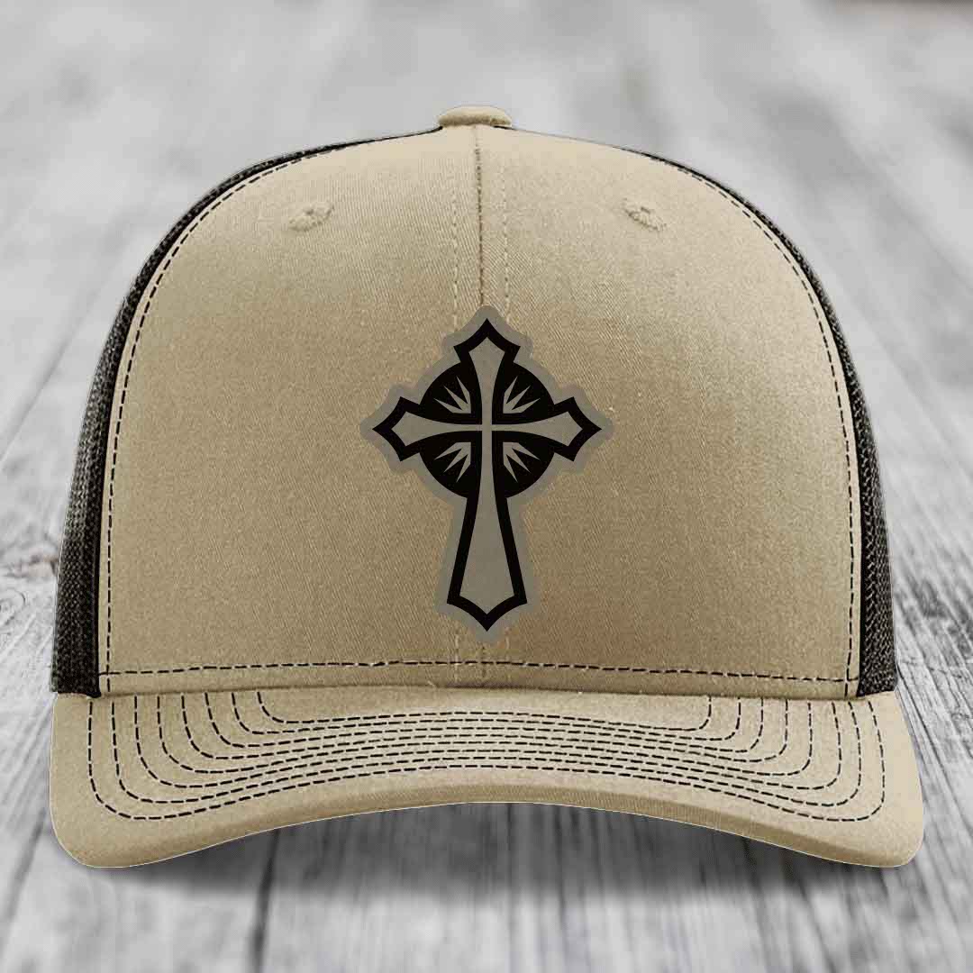 Beige trucker hat with black cross patch on front, black mesh back and stitched brim.