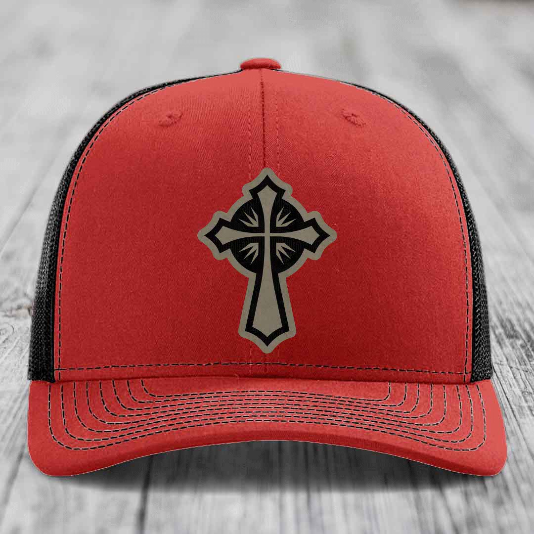 Red trucker hat with black mesh back and grey cross leather patch on front.