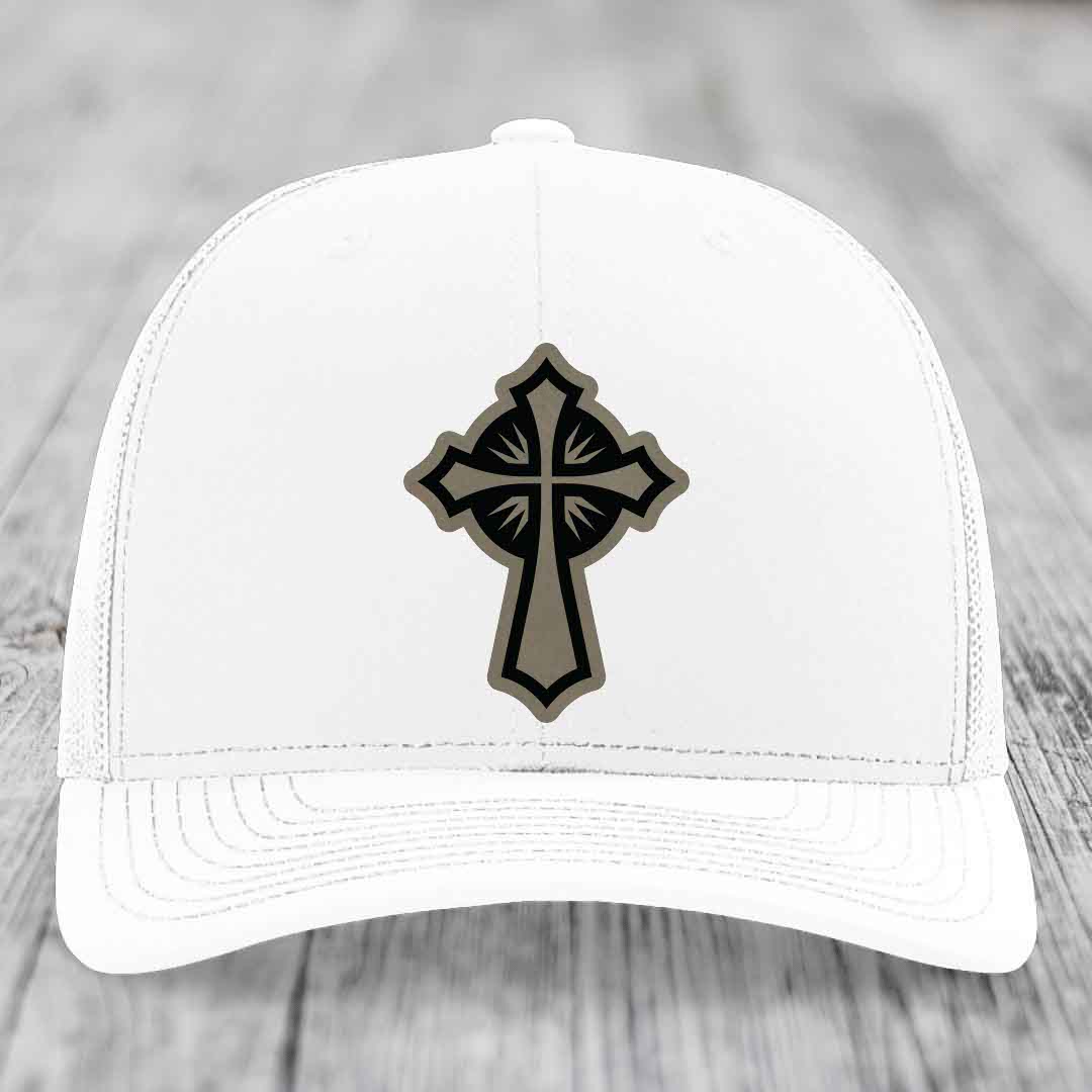 White trucker hat with a black and grey cross leather patch on the front.