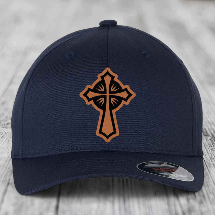 Dark blue baseball cap with a brown leatherette cross patch on the front.