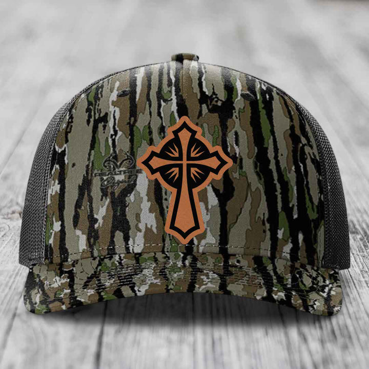 Camouflage trucker hat with brown leather cross patch on front.
