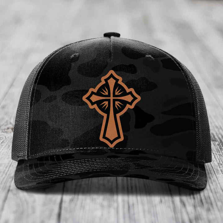 Black camouflage trucker hat with brown cross patch on front.