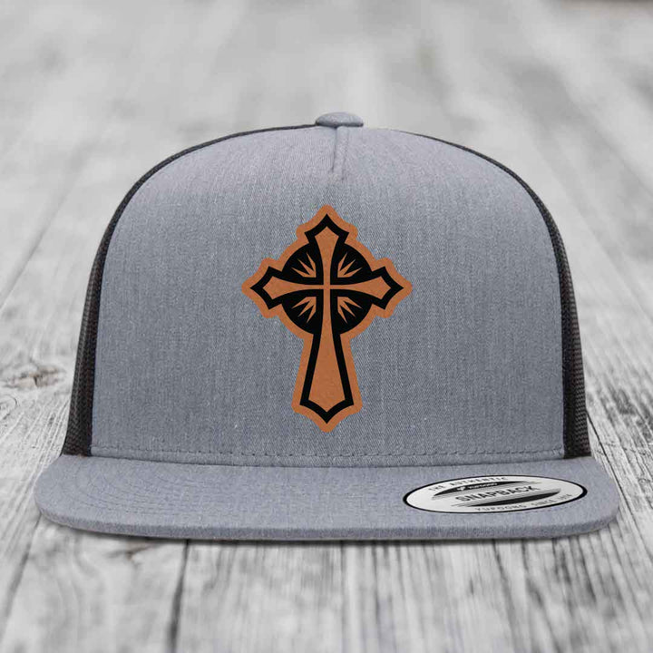 Grey trucker hat with a brown and black cross leather patch on front.