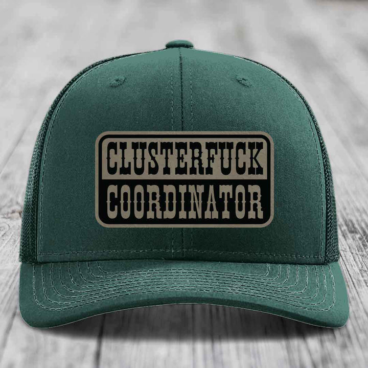 Dark green trucker hat with a rectangular leather patch reading &