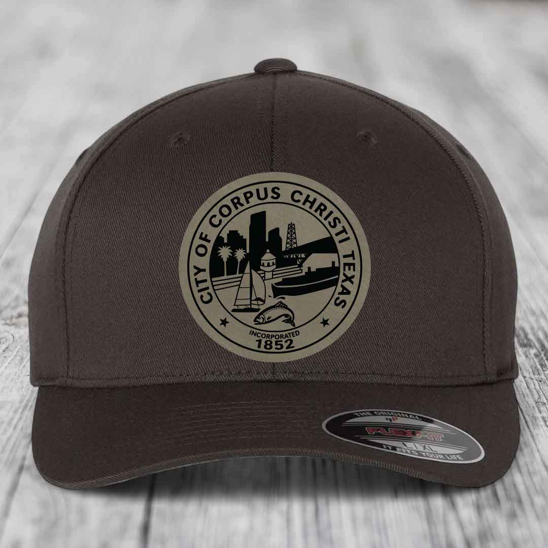 Dark brown Flexfit hat with Corpus Christi Texas city seal patch featuring skyline, boat, and fish design.