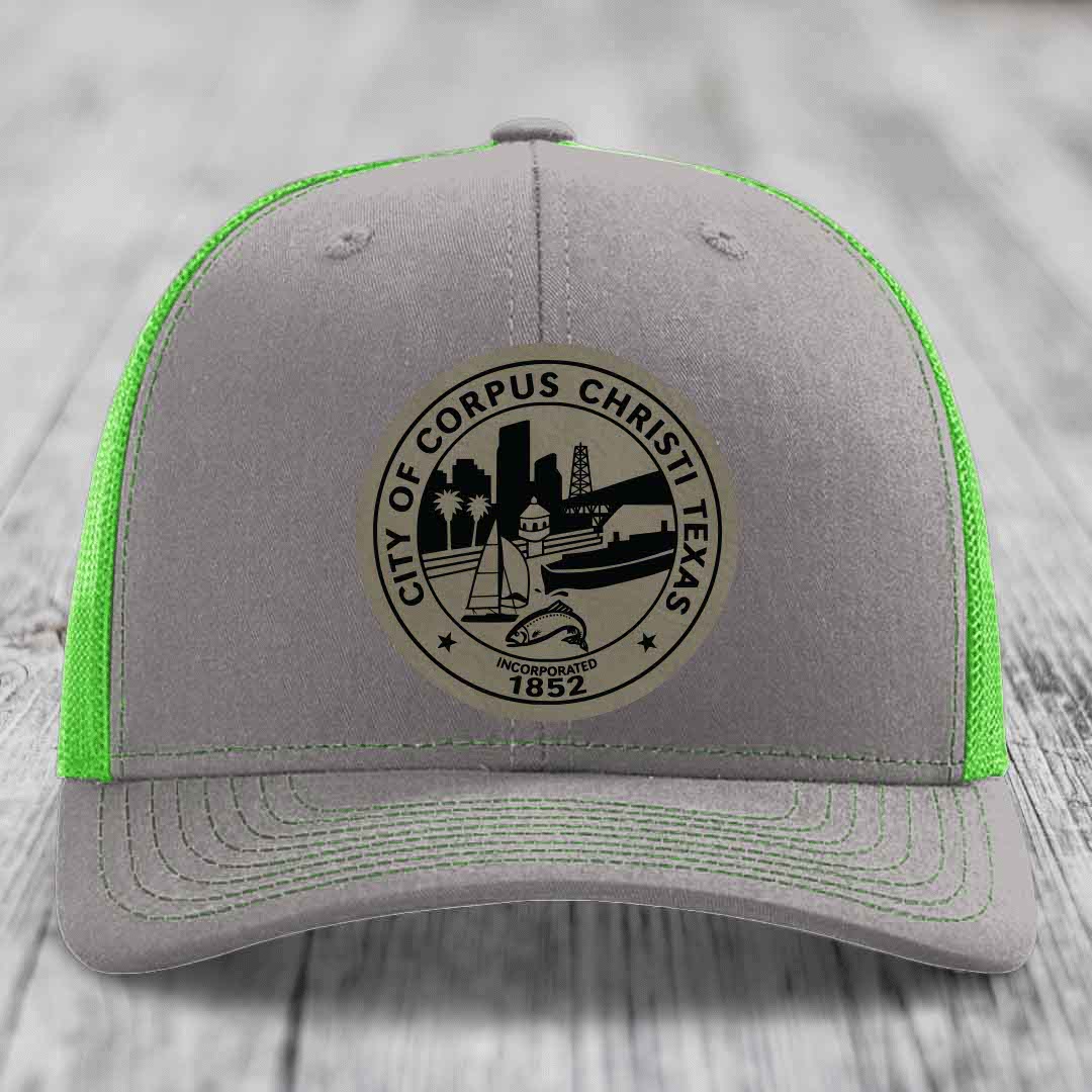 Grey trucker hat with neon green mesh and stitching, featuring a circular Corpus Christi Texas seal patch.