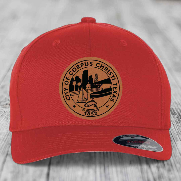Red baseball cap with circular Corpus Christi, Texas leather patch featuring city skyline and fish emblem.