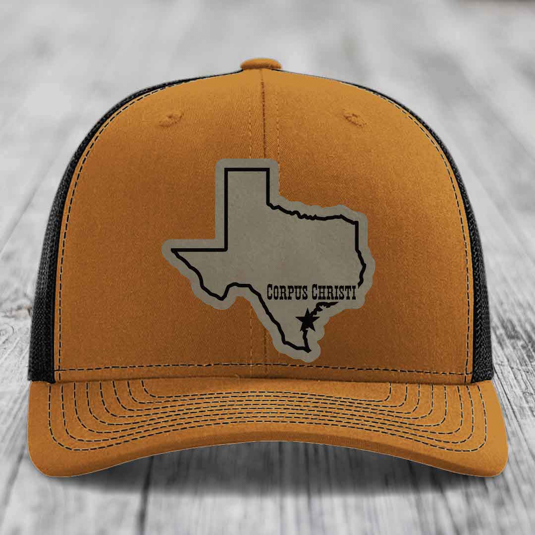 Grey trucker hat with black mesh back and a tan leather patch of Texas with &