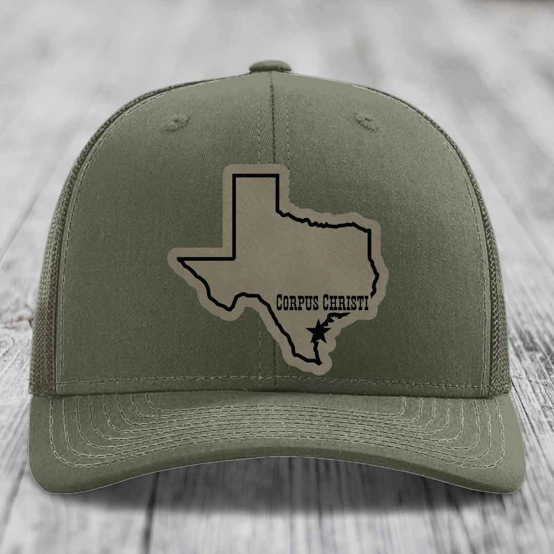 Olive green trucker hat with a beige leather patch showing the state of Texas and &