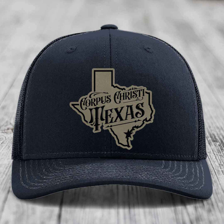 Purple trucker hat with a beige and black Corpus Christi, Texas patch shaped like the state of Texas.