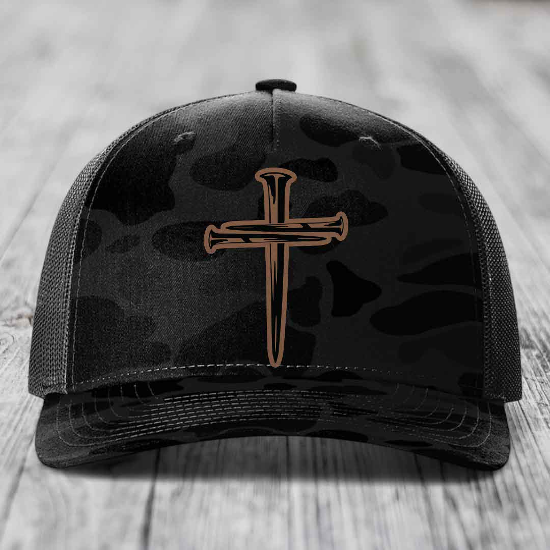 Camouflage trucker hat with a cross made of nails patch on front.