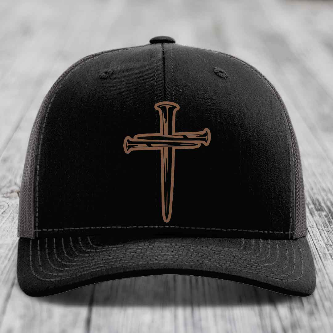 Black trucker hat with brown cross of nails patch and white stitching on front panel.