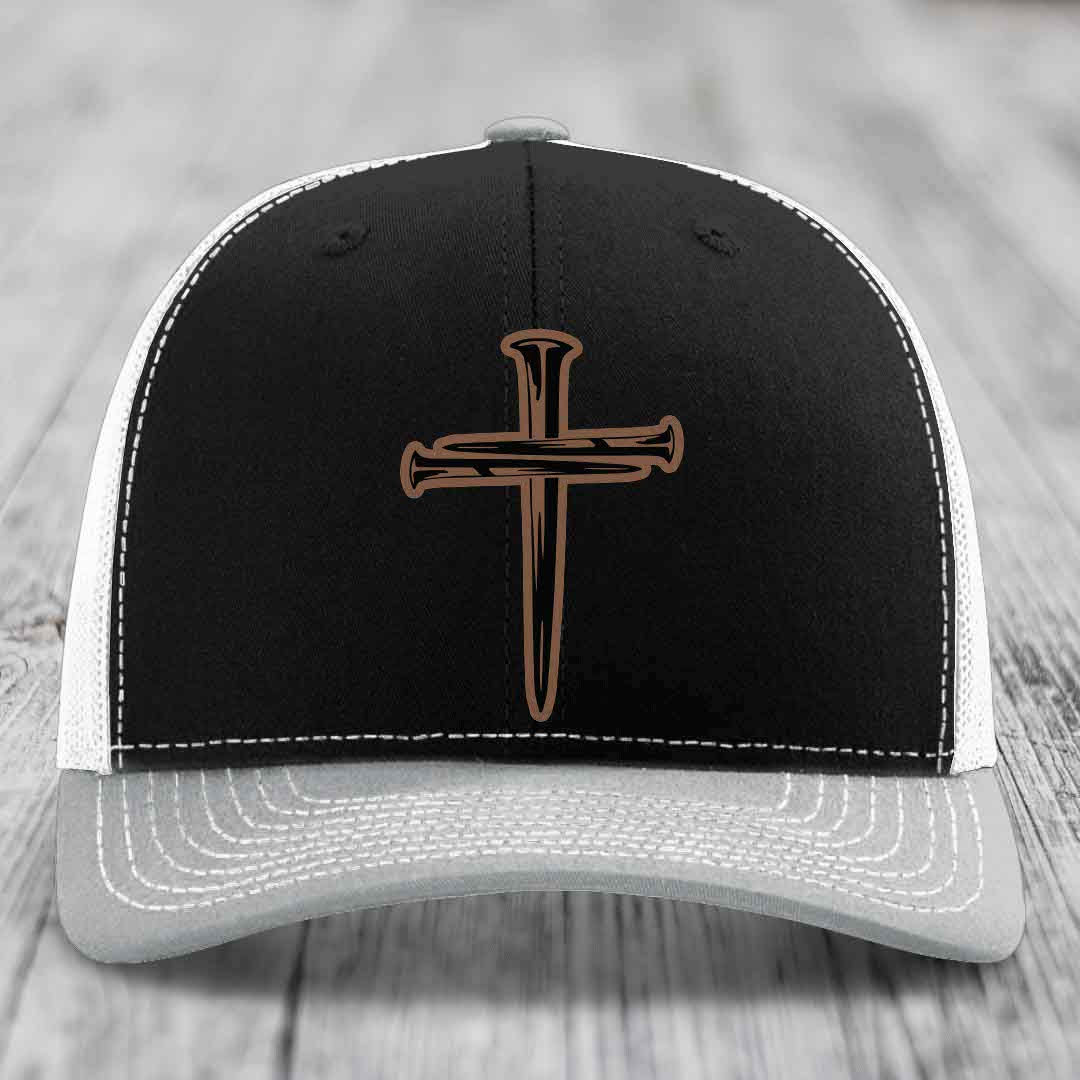 Brown trucker hat with cross of nails patch and white stitching on front panel.