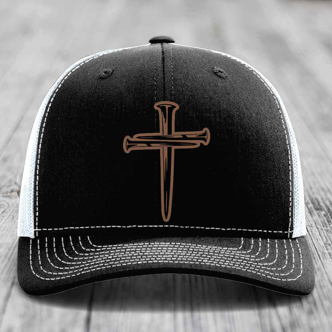 Black trucker hat with brown cross of nails patch on front, white mesh back and gray brim.