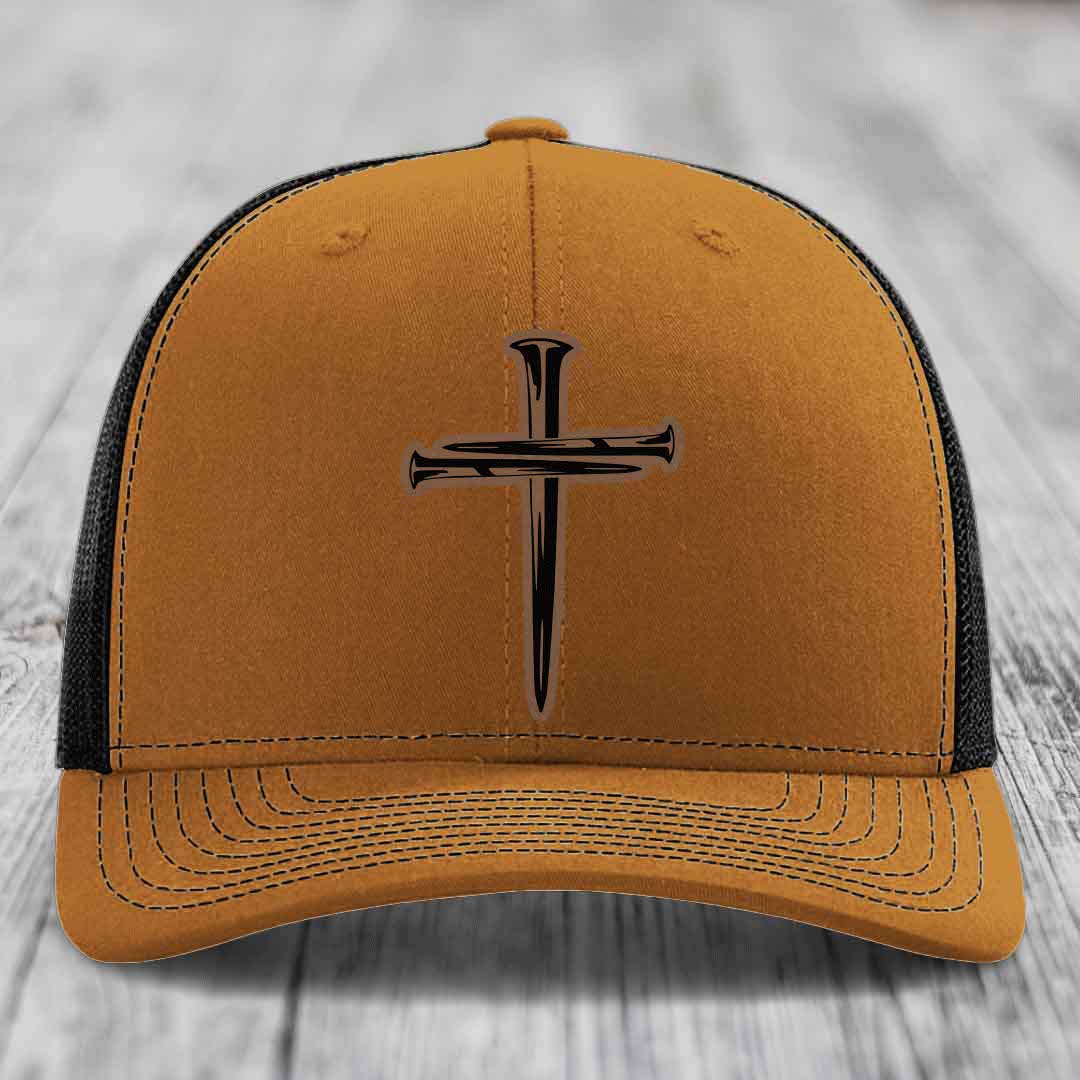 Grey trucker hat with black mesh back and a cross made of nails patch on front.