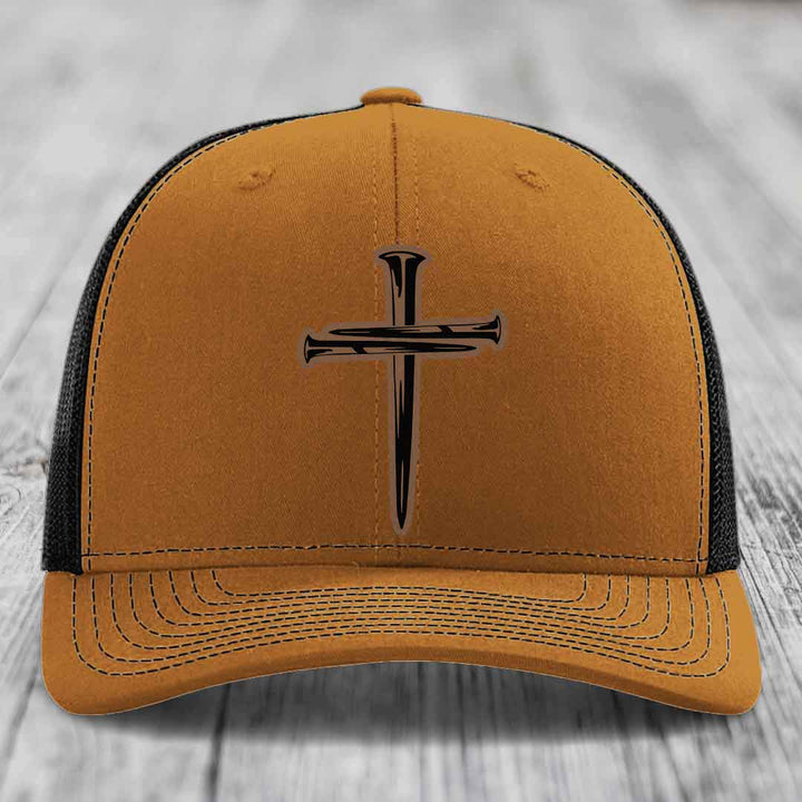 Grey trucker hat with black mesh back and a cross made of nails patch on front.