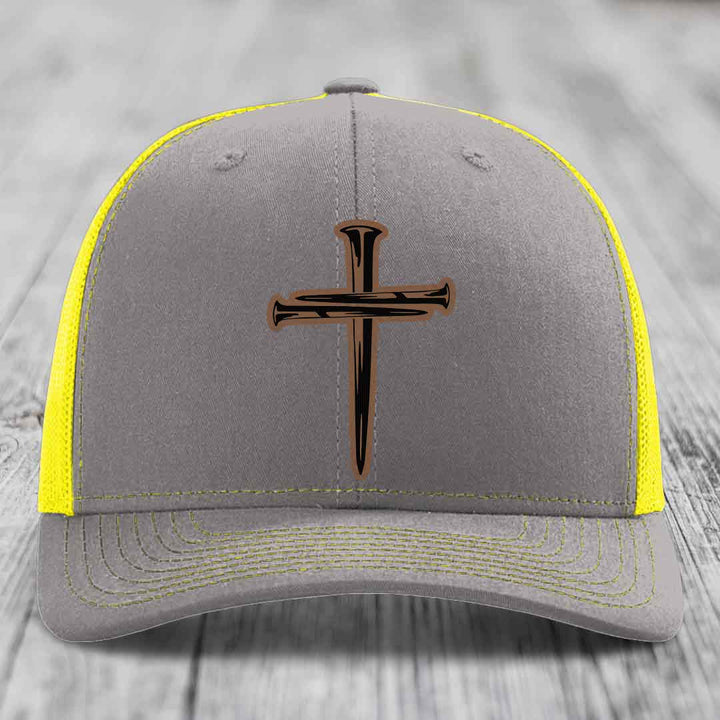 Brown trucker hat with a cross made of nails patch on front.