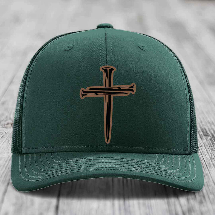 Grey trucker hat with a cross made of nails patch on front.