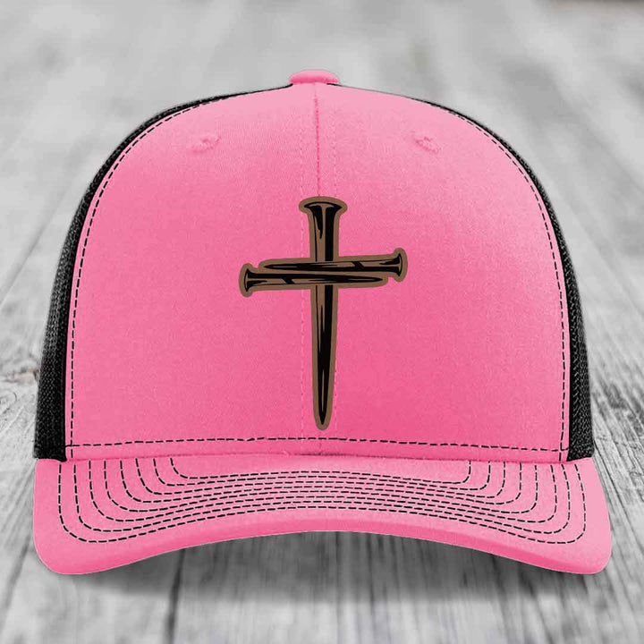 Green trucker hat with white mesh back and embroidered cross of nails patch.